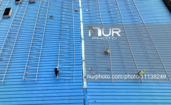 Workers are installing solar photovoltaic panels on the roof of a factory in Haian, Jiangsu Province, China, on April 11, 2024. 