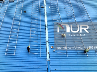 Workers are installing solar photovoltaic panels on the roof of a factory in Haian, Jiangsu Province, China, on April 11, 2024. (