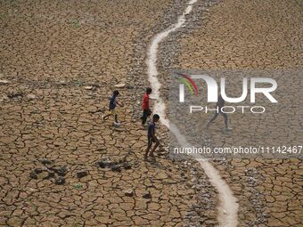 Children are crossing a dried-up lake at Boklung near Kathiatoli in Nagaon District, Assam, India, on April 13, 2024. (