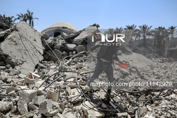 A Palestinian man is walking near the Abu Bakr Al-Siddiq Mosque, which was leveled by Israeli bombardment in Deir Al-Balah, in the central G...