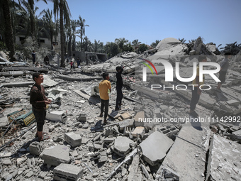 Palestinians are inspecting the damage in the rubble of Abu Bakr Al-Siddiq Mosque, which was leveled by Israeli bombardment in Deir Al-Balah...