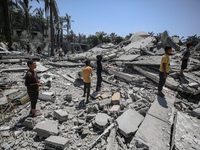 Palestinians are inspecting the damage in the rubble of Abu Bakr Al-Siddiq Mosque, which was leveled by Israeli bombardment in Deir Al-Balah...