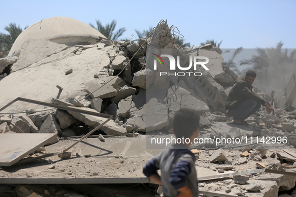 Palestinians are inspecting the damage in the rubble of Abu Bakr Al-Siddiq Mosque, which was leveled by Israeli bombardment in Deir Al-Balah...