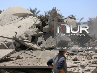 Palestinians are inspecting the damage in the rubble of Abu Bakr Al-Siddiq Mosque, which was leveled by Israeli bombardment in Deir Al-Balah...