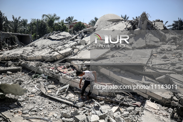 A Palestinian boy is sitting near the Abu Bakr Al-Siddiq Mosque, which was leveled by Israeli bombardment in Deir Al-Balah, in the central G...