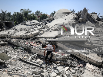 A Palestinian boy is sitting near the Abu Bakr Al-Siddiq Mosque, which was leveled by Israeli bombardment in Deir Al-Balah, in the central G...