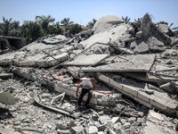 A Palestinian boy is sitting near the Abu Bakr Al-Siddiq Mosque, which was leveled by Israeli bombardment in Deir Al-Balah, in the central G...