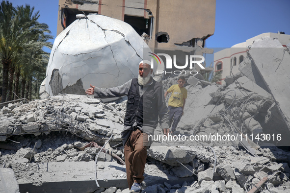 A Palestinian man is reacting near the Abu Bakr Al-Siddiq Mosque, which has been leveled by Israeli bombardment in Deir Al-Balah, in the cen...