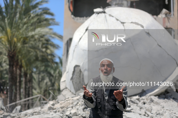 A Palestinian man is reacting near the Abu Bakr Al-Siddiq Mosque, which has been leveled by Israeli bombardment in Deir Al-Balah, in the cen...