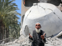 A Palestinian man is reacting near the Abu Bakr Al-Siddiq Mosque, which has been leveled by Israeli bombardment in Deir Al-Balah, in the cen...