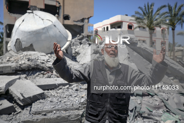 A Palestinian man is reacting near the Abu Bakr Al-Siddiq Mosque, which has been leveled by Israeli bombardment in Deir Al-Balah, in the cen...