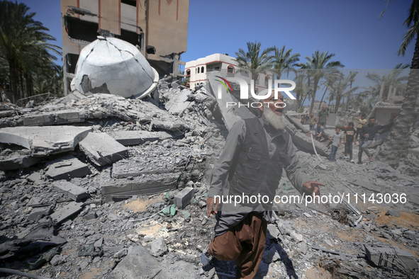 A Palestinian man is reacting near the Abu Bakr Al-Siddiq Mosque, which has been leveled by Israeli bombardment in Deir Al-Balah, in the cen...