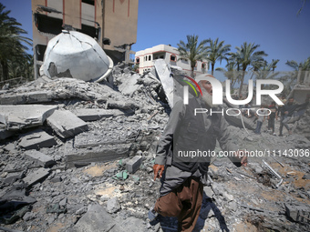 A Palestinian man is reacting near the Abu Bakr Al-Siddiq Mosque, which has been leveled by Israeli bombardment in Deir Al-Balah, in the cen...