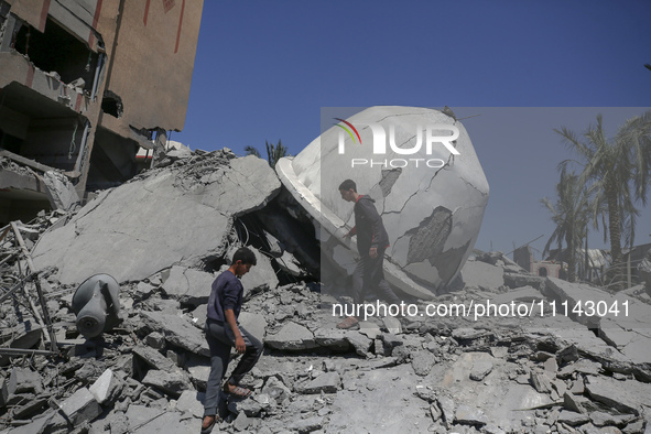 Palestinians are inspecting the damage in the rubble of Abu Bakr Al-Siddiq Mosque, which was leveled by Israeli bombardment in Deir Al-Balah...