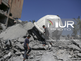 Palestinians are inspecting the damage in the rubble of Abu Bakr Al-Siddiq Mosque, which was leveled by Israeli bombardment in Deir Al-Balah...