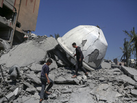 Palestinians are inspecting the damage in the rubble of Abu Bakr Al-Siddiq Mosque, which was leveled by Israeli bombardment in Deir Al-Balah...