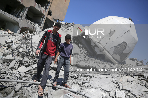 Palestinians are inspecting the damage in the rubble of Abu Bakr Al-Siddiq Mosque, which was leveled by Israeli bombardment in Deir Al-Balah...