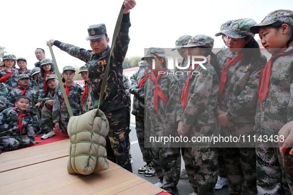 A military experience camp instructor is teaching primary school students how to carry a backpack in Lianyungang, China, on April 13, 2024. 