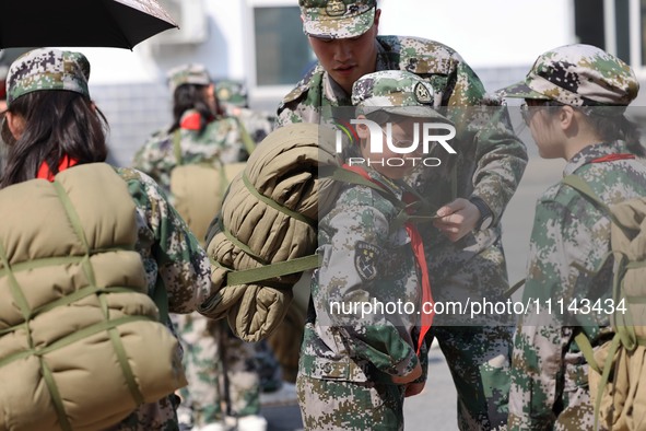 A military experience camp instructor is teaching primary school students how to carry a backpack in Lianyungang, China, on April 13, 2024. 