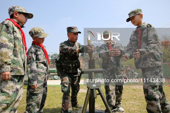 An instructor at a military experience camp is teaching elementary school students how to simulate the firing of a ''mortar'' in Lianyungang...