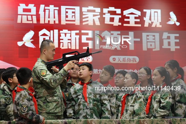 An instructor at a military experience camp is explaining the use of weapons to primary school students in Lianyungang, China, on April 13,...