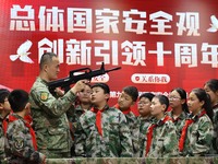 An instructor at a military experience camp is explaining the use of weapons to primary school students in Lianyungang, China, on April 13,...