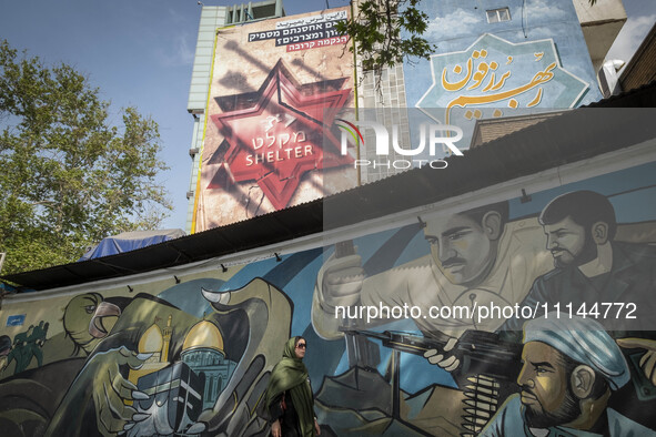 An Iranian woman is walking under anti-Israeli murals in downtown Tehran, Iran, on April 13, 2024. The Prime Minister of Israel, Benjamin Ne...