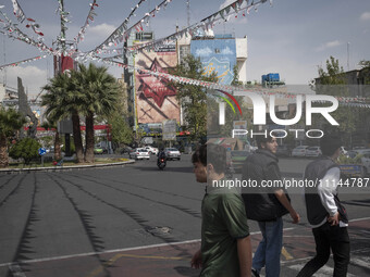 Young Iranian men are crossing a street while an anti-Israeli mural is visible on a wall in downtown Tehran, Iran, on April 13, 2024. The Pr...