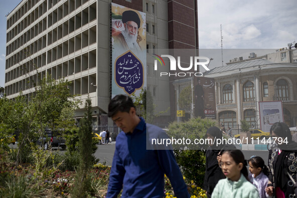 A family is walking under a massive portrait of Iran's Supreme Leader Ayatollah Ali Khamenei in southern Tehran, Iran, on April 13, 2024. Th...