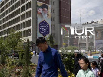 A family is walking under a massive portrait of Iran's Supreme Leader Ayatollah Ali Khamenei in southern Tehran, Iran, on April 13, 2024. Th...