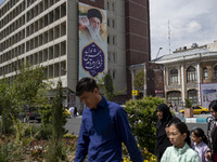 A family is walking under a massive portrait of Iran's Supreme Leader Ayatollah Ali Khamenei in southern Tehran, Iran, on April 13, 2024. Th...