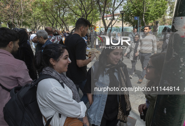 Young Iranian women, who are not wearing mandatory headscarves, are speaking with each other while standing on a sidewalk near the Grand Baz...