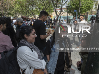 Young Iranian women, who are not wearing mandatory headscarves, are speaking with each other while standing on a sidewalk near the Grand Baz...