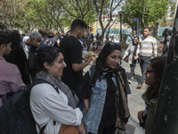 Young Iranian women, who are not wearing mandatory headscarves, are speaking with each other while standing on a sidewalk near the Grand Baz...