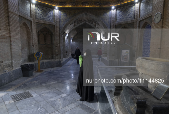 A veiled Iranian woman, responsible for enjoining good and forbidding evil, is standing at the Grand Bazaar in southern Tehran, Iran, on Apr...