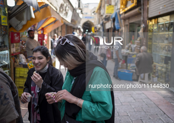 Two young Iranian women, who are not wearing mandatory headscarves, are walking together along a street near the Grand Bazaar in southern Te...