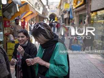 Two young Iranian women, who are not wearing mandatory headscarves, are walking together along a street near the Grand Bazaar in southern Te...