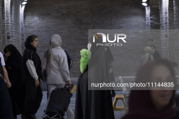 A veiled Iranian official responsible for enjoining good and forbidding evil is monitoring women at the Grand Bazaar in southern Tehran, Ira...