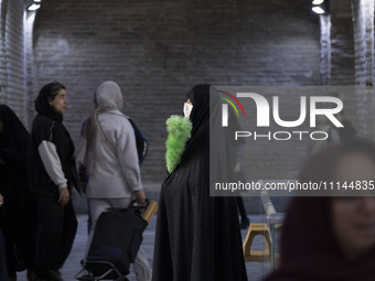 A veiled Iranian official responsible for enjoining good and forbidding evil is monitoring women at the Grand Bazaar in southern Tehran, Ira...