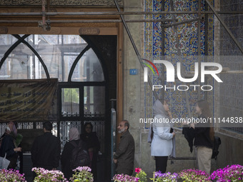 A young Iranian woman, who is not wearing a mandatory headscarf, is adjusting her scarf to enter the Grand Bazaar in southern Tehran, Iran,...