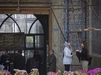 A young Iranian woman, who is not wearing a mandatory headscarf, is adjusting her scarf to enter the Grand Bazaar in southern Tehran, Iran,...