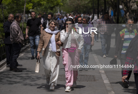 Two young Iranian women, who are not wearing mandatory headscarves, are walking together along a street near the Grand Bazaar in southern Te...