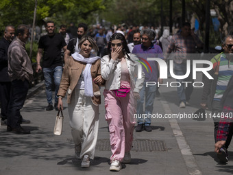 Two young Iranian women, who are not wearing mandatory headscarves, are walking together along a street near the Grand Bazaar in southern Te...