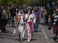 Two young Iranian women, who are not wearing mandatory headscarves, are walking together along a street near the Grand Bazaar in southern Te...