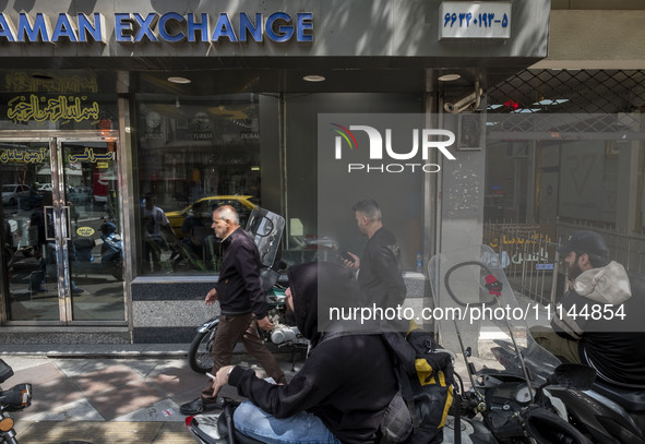 Iranian street money changers are sitting outside a currency exchange shop in Tehran's business district, Iran, on April 13, 2024. Meanwhile...