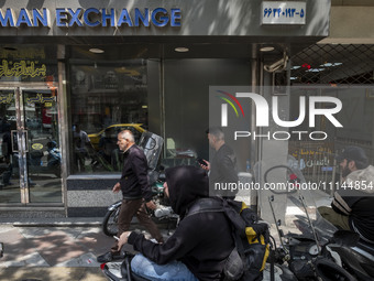 Iranian street money changers are sitting outside a currency exchange shop in Tehran's business district, Iran, on April 13, 2024. Meanwhile...