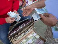 Two men are holding Iranian banknotes on a sidewalk in Tehran's business district, in Tehran, Iran, on April 13, 2024. Meanwhile, the Prime...