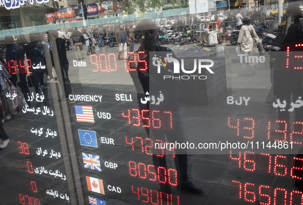 An Iranian man is looking at an electronic board displayed at a currency exchange shop in Tehran's business district, Iran, on April 13, 202...