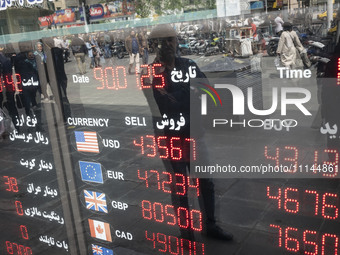 An Iranian man is looking at an electronic board displayed at a currency exchange shop in Tehran's business district, Iran, on April 13, 202...