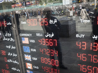 An Iranian man is looking at an electronic board displayed at a currency exchange shop in Tehran's business district, Iran, on April 13, 202...